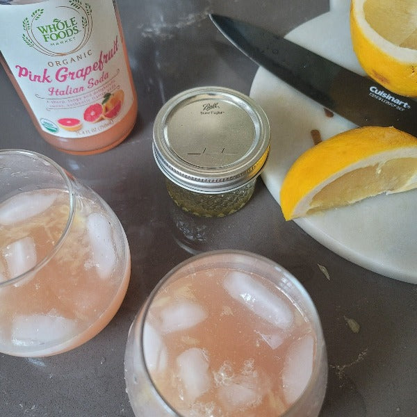 Pink grapefruit recipe using our botanical terpene infused agave.  Picture of the agave, drinks and ingredients (pink grapefruit soda, grapefruit slices squeezed into glasses